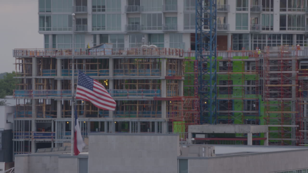 Bandiera americana e bandiera del Texas che sventolano davanti a un cantiere edile ad Austin, Texas