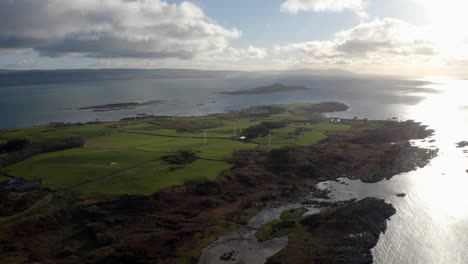 AERIAL---Wind-power-turbines-at-sunrise,-Isle-of-Gigha,-Kintyre,-Scotland,-lowering