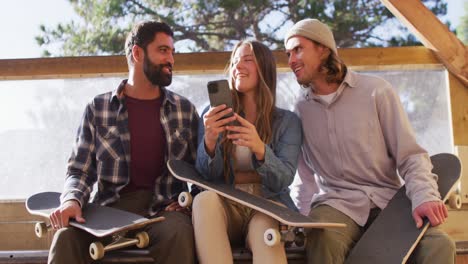 video of happy diverse female and male skateboarders in skate park