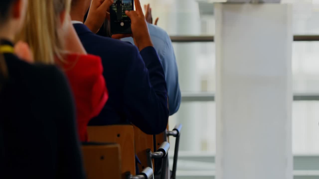 Pebisnis bertepuk tangan untuk pembicara pria di seminar bisnis 4k