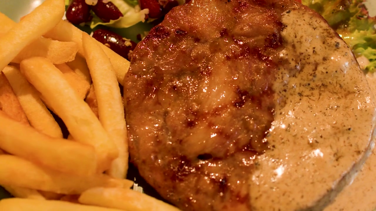 Primo piano di una bistecca alla griglia con salsa ai funghi, patatine fritte e insalata fresca