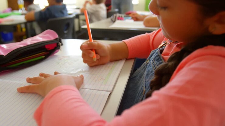 Estudiante caucásica estudiando en su pupitre en un aula escolar 4K