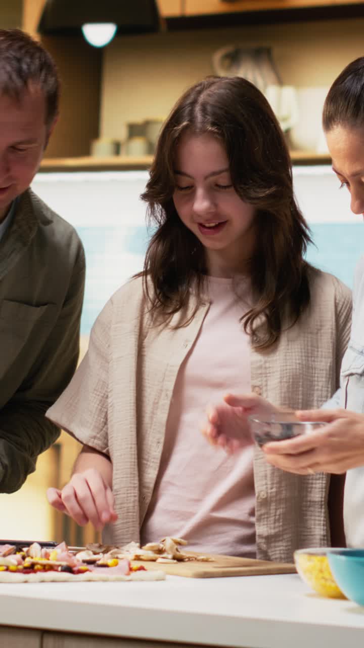 Vertical Video Family preparing homemade pizza together by adding fresh ingredients