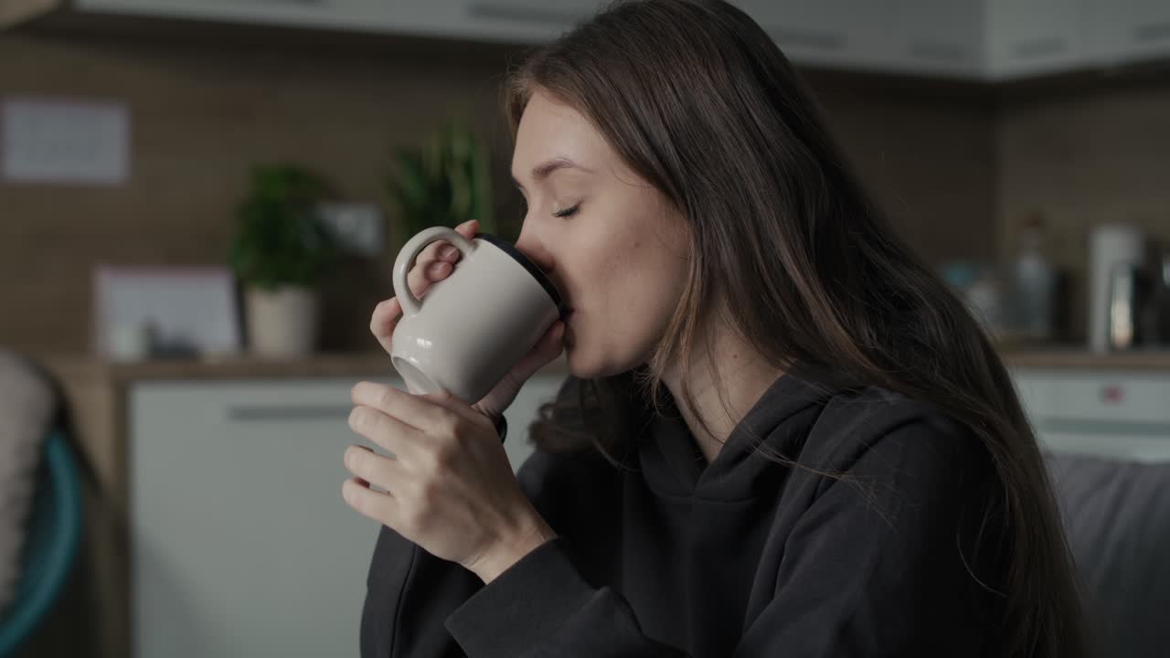 Mujer caucásica triste sentada en el sofá con una taza de café