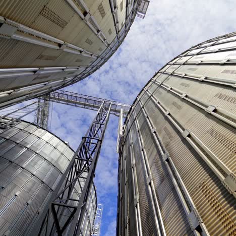 aluminum containers for storing grains. exterior of large metal elevators. close-up. view from below. camera motion around.