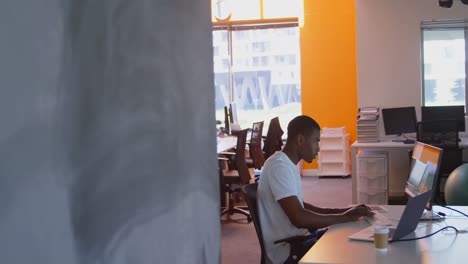 side view of young black male executive working on computer at desk in modern office 4k