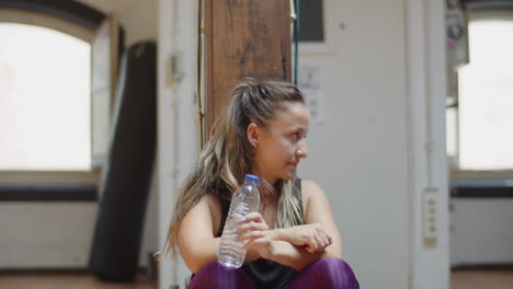 Front-view-of-happy-dance-teacher-sitting-on-floor-after-class