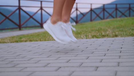 mujer saltando al aire libre en un parque con montañas en el fondo