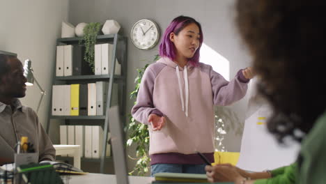 young asian woman giving business presentation to colleagues