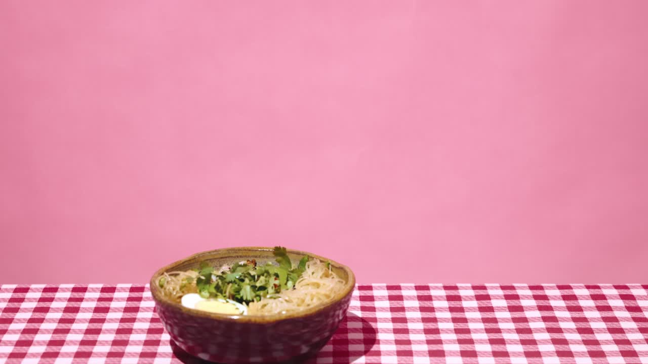 añadiendo cilantro a un plato de fideos