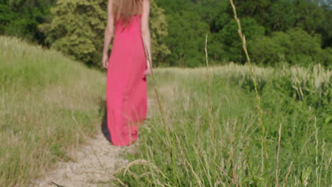 a woman in a red dress walks through a nature landscape