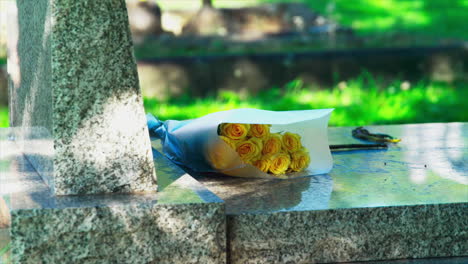 a bouquet of yellow flowers on a marble gravestone