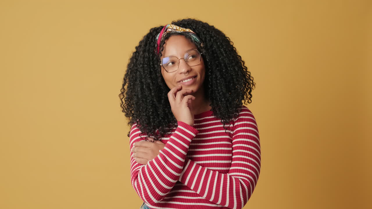 Thoughtful Young Woman Pondering and Smiling on Yellow Background