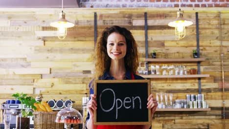 Portrait-of-smiling-waitresses-holding-open-sign-board