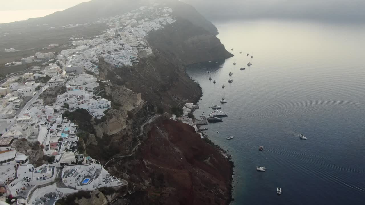 vista de avión no tripulado en grecia volando sobre santorini con la ciudad de oia casas blancas en un acantilado junto al mar mediterráneo al amanecer