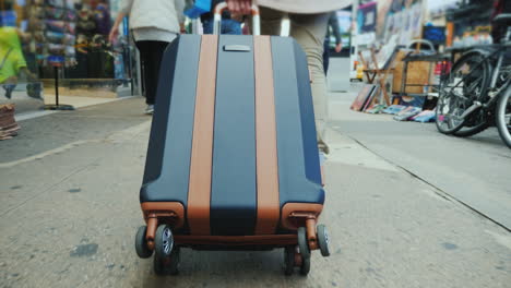 a person with a bag on wheels goes down the busy sidewalk of manhattan in new york only legs are vis