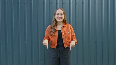 smiling woman pointing down and giving a thumbs-up on an isolated background