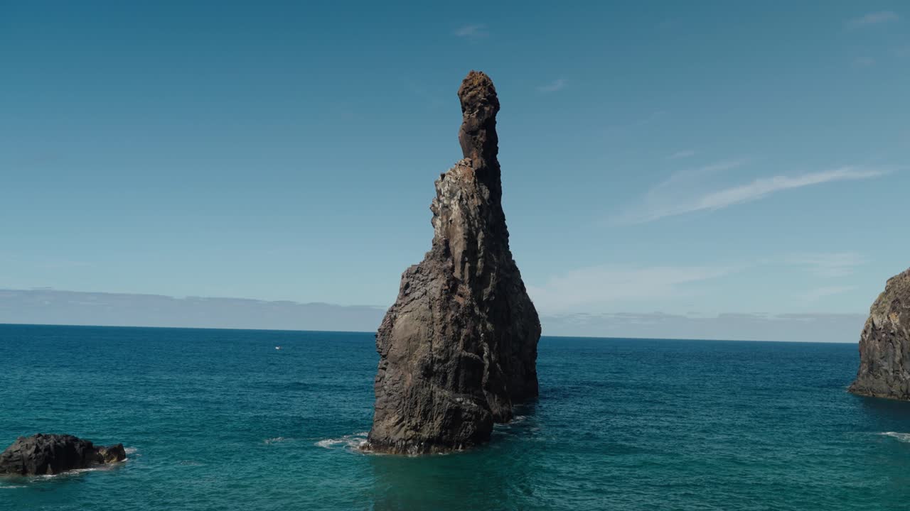 tilt-up shot of the Ilhéus sea stack rising from the Atlantic, emphasizing its dramatic height and isolated stance against the horizon.