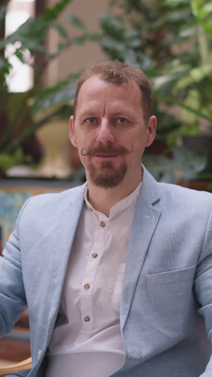 Man artist fixes mustache sitting on chair. Painter seamlessly integrates moment of personal grooming in immersive experience of drawing process in studio