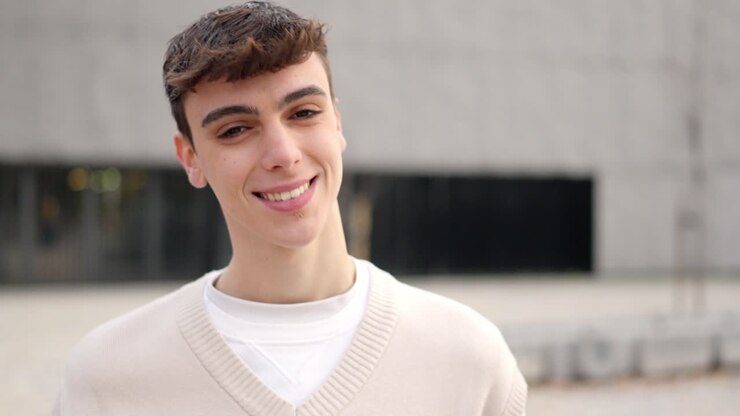 Cool caucasian young man looking at camera and smiling outdoors