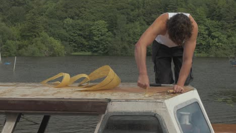 carpenter removes old epoxy fiberglass resin on cabin roof planking wooden boat maintenance