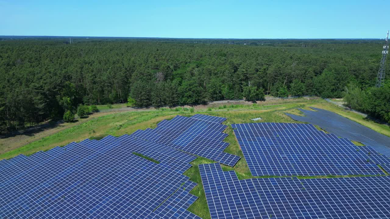 Photovoltaic panels providing clean energy in a solar farm on hill near a forest in Germany. Nice aerial view flight fly reverse drone