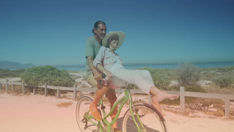 puntos de luz contra una pareja de ancianos caucásicos montando en una bicicleta juntos en la playa