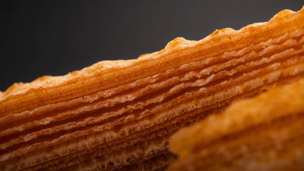 Lo spostamento della messa a fuoco, la telecamera rivela una fetta di pasticcino in studio, briciole e un pezzo adiacente, mostrando gli strati.