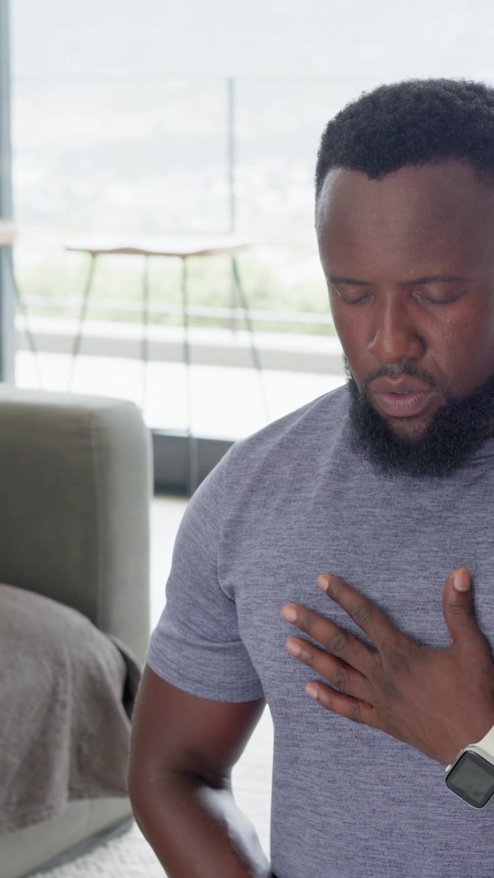 Vertical video: After sitting at home, breathing man bringing hand thigh-to-belly to calm in tee