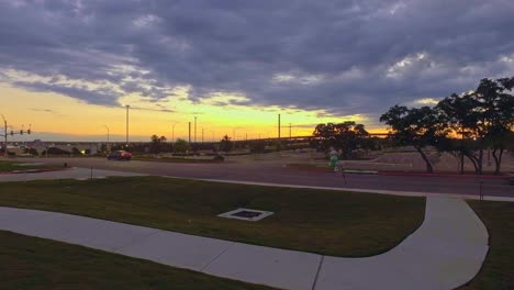 Cars-leaving-apartments-for-work-early-morning-commute-with-sunrise-in-the-background-and-vacant-car-park-ahead