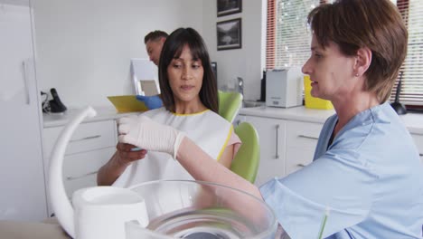 enfermera dental caucásica hablando y preparando a una paciente en una clínica dental moderna