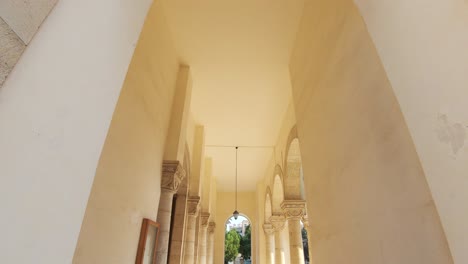 Archway-view-of-lateral-hallway-of-Church-of-the-holy-Trinity-in-Limassol,-Cyprus---Wide-Tilt-down-shot