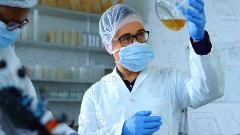 chemical formulas animation over scientist examining liquid in laboratory flask