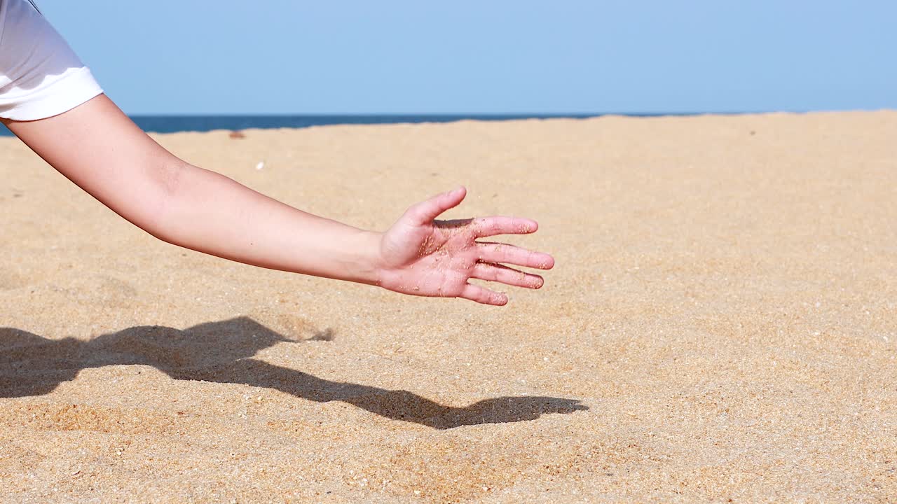 Hand sifting sand on a sunny beach