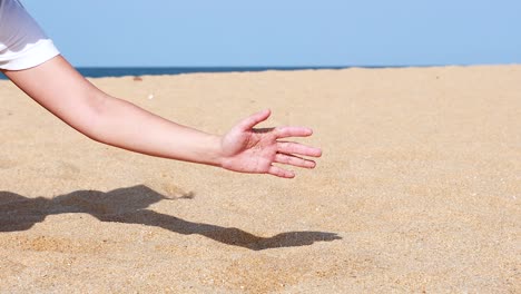 hand sifting sand on a sunny beach