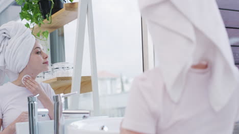 a young woman cleaning her face with a cotton pad