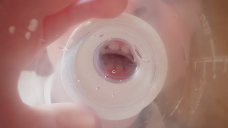 un niño pequeño bebe agua sosteniendo una botella de plástico con un pezón