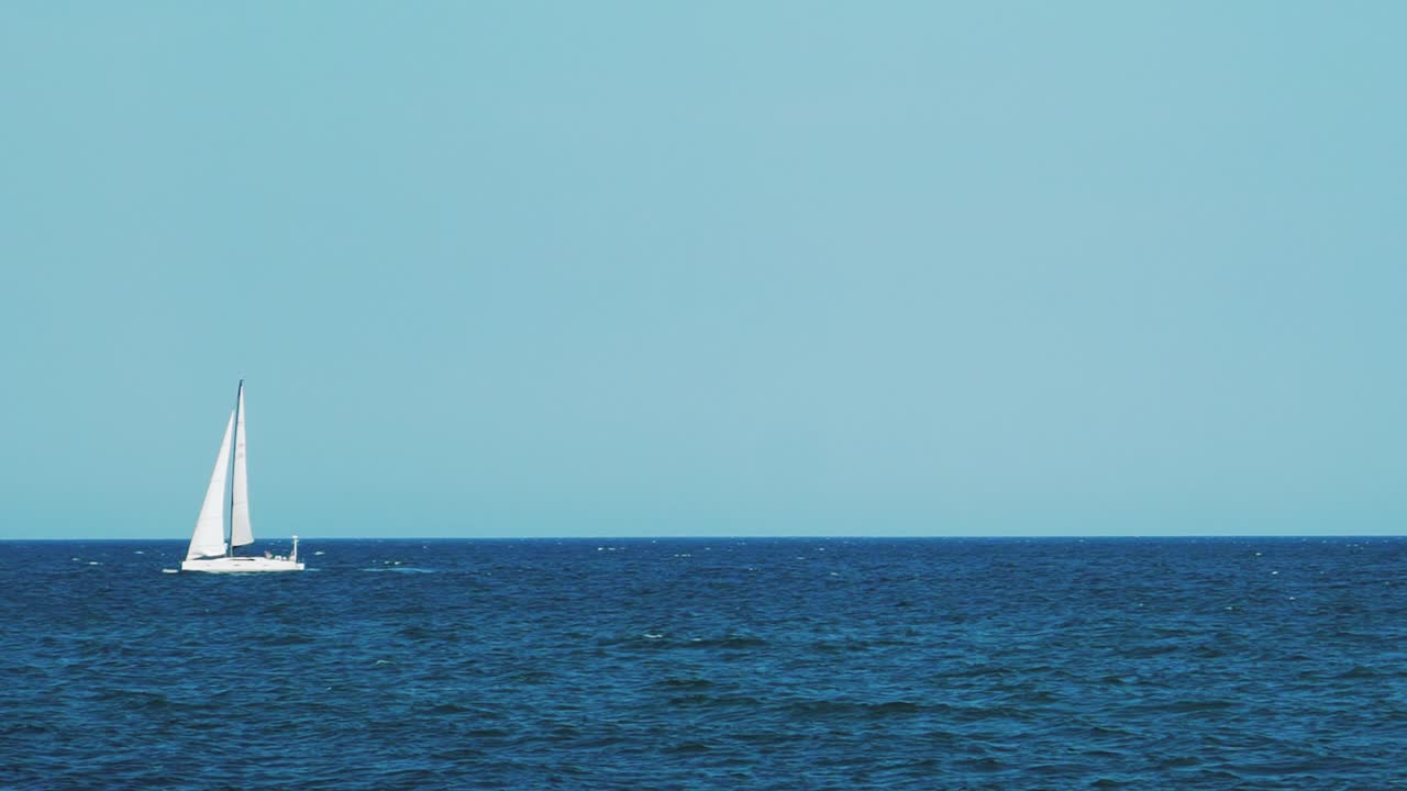 A sailboat, yacht on the horizon in the sea. Horizon of the sea. Blue water and sky
