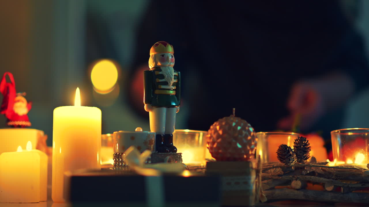 Soft candlelight illuminates beautifully arranged festive decorations, including a nutcracker and various ornaments, creating a warm and inviting holiday atmosphere