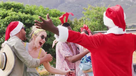 Happy-group-of-diverse-friends-embracing-at-christmas-party-in-garden