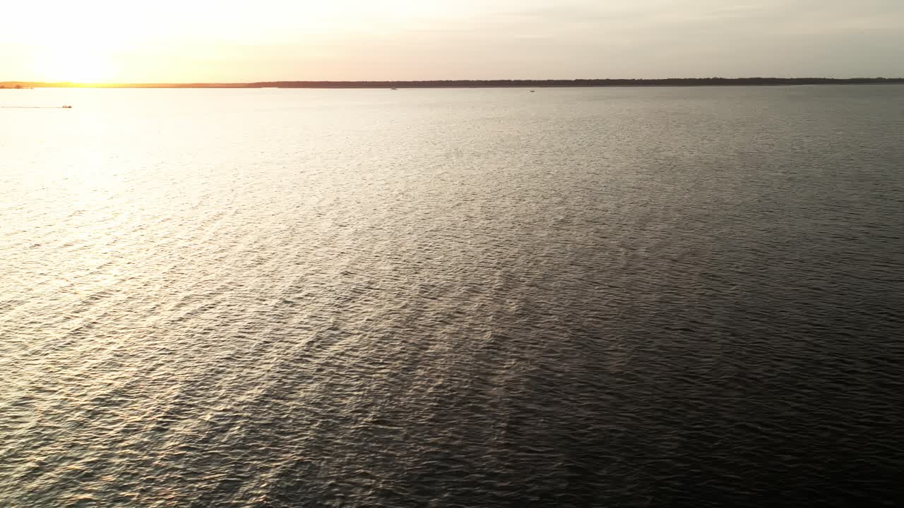 Empty calm waters under sunset glow with horizon fading into sky, no boats or people seen