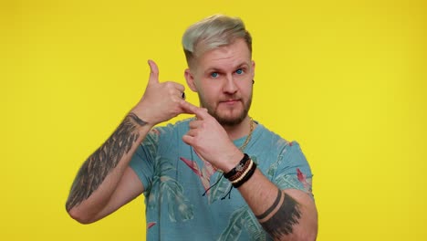 bearded man in t-shirt looking at camera doing phone gesture like says hey you call me back