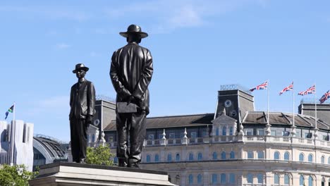 two statues on plinth with flags and building