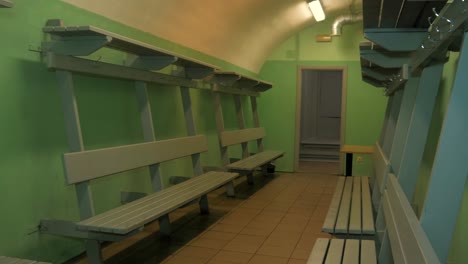 interior of the concrete bomb shelter to hide civil people, an underground apocalypse bunker built in old coastal fortification, gray wooden benches, wide handheld shot