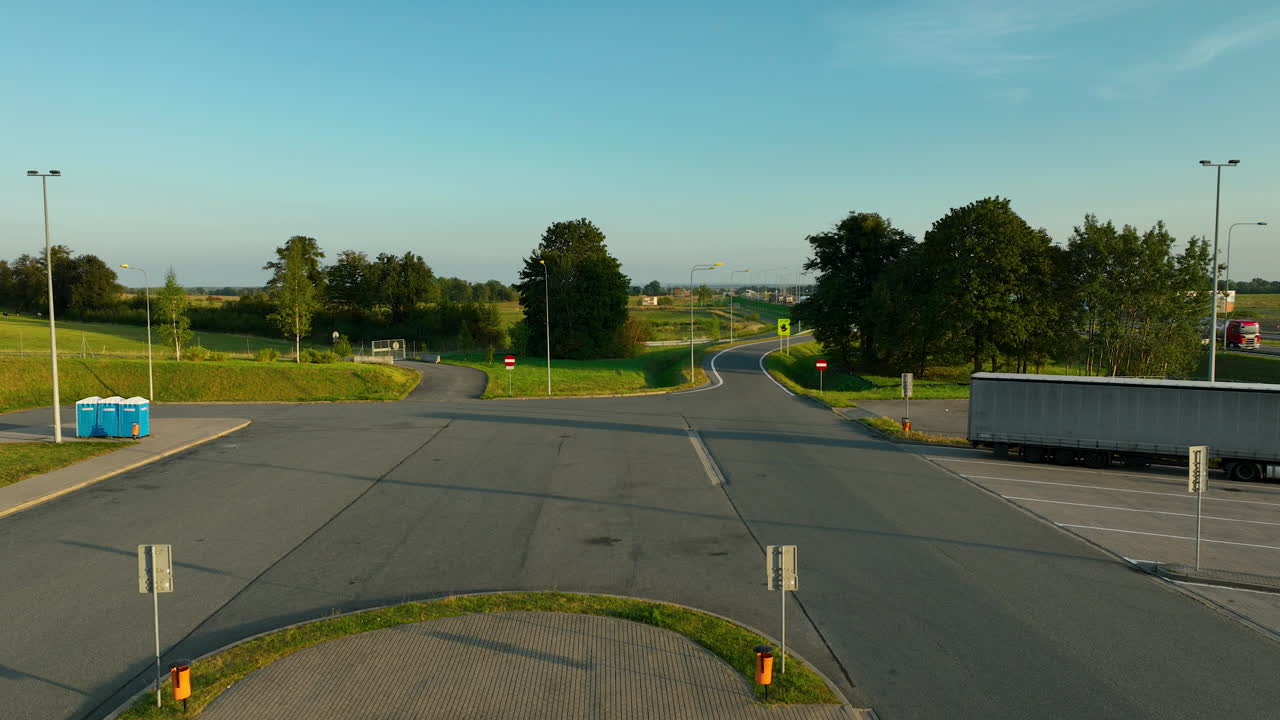 vista a nivel del suelo de una zona de descanso de la carretera, que muestra plazas de estacionamiento, incluido un lugar de estacionamiento accesible designado, bajo un cielo despejado durante la tarde temprana