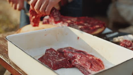 male hands cutting raw meat for grilling outdoors