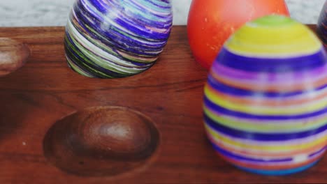 three decorated easter eggs on a wood plate