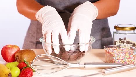 hands arranging chocolate discs in a bowl