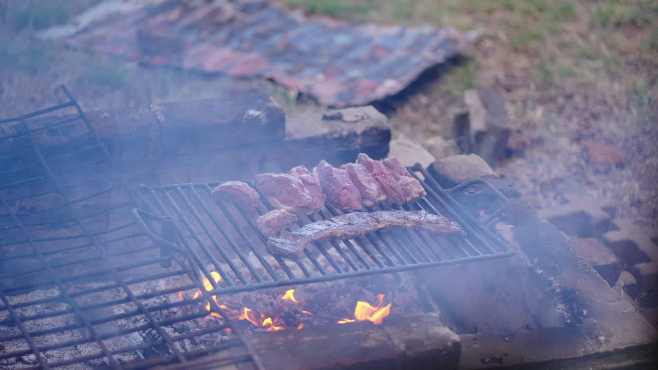 Outdoor grill with skirt steak (entraña) and picanha over open fire pit