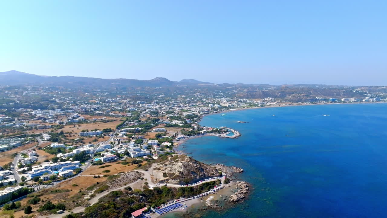 Aerial view flying backwards over the Faliraki town in Rhodes, in sunny Greece